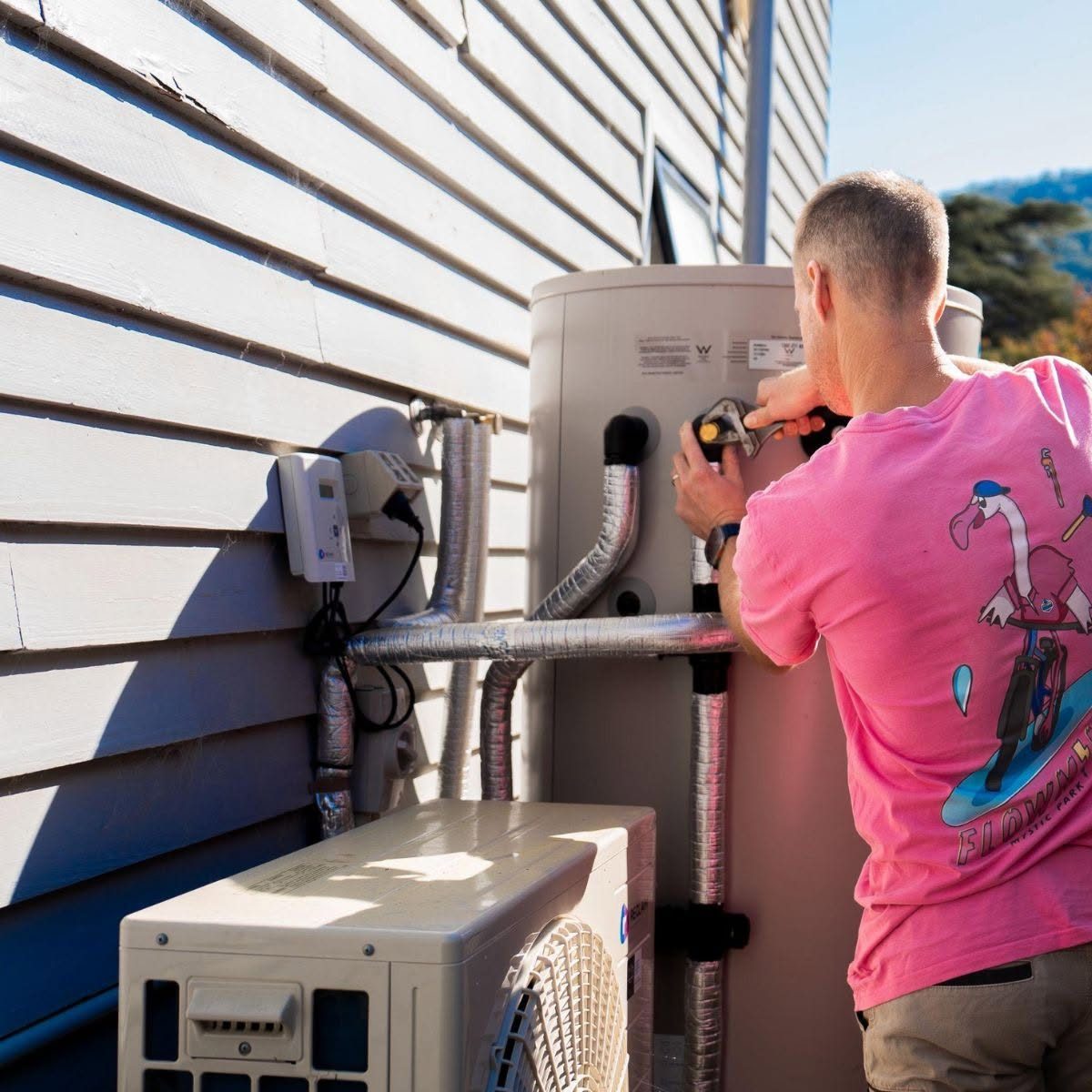 Plumber installing an outdoor hot water unit
